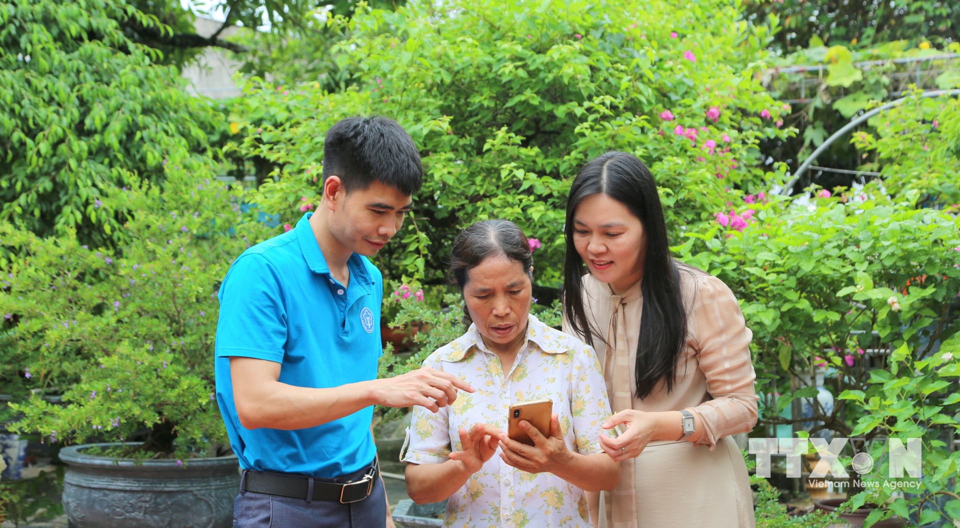 Đại diện Bảo hiểm xã hội thành phố Hải Phòng hướng dẫn người dân tiếp cận thông tin bảo hiểm xã hội, bảo hiểm y tế trên nền tảng số. (Ảnh: Minh Thu/TTXVN)